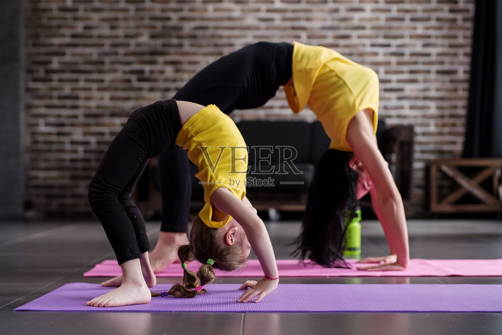 两个柔韧的不同年龄的女孩做向上弓瑜伽的姿势锻炼照片摄影图片