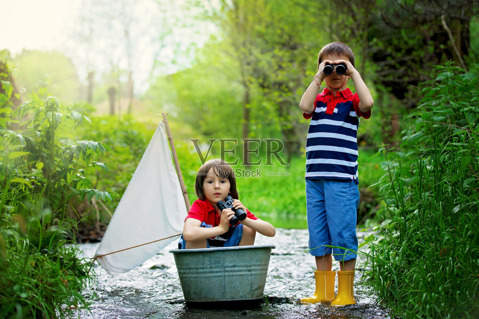 可爱的孩子们，男孩们，在小河上玩小船照片摄影图片
