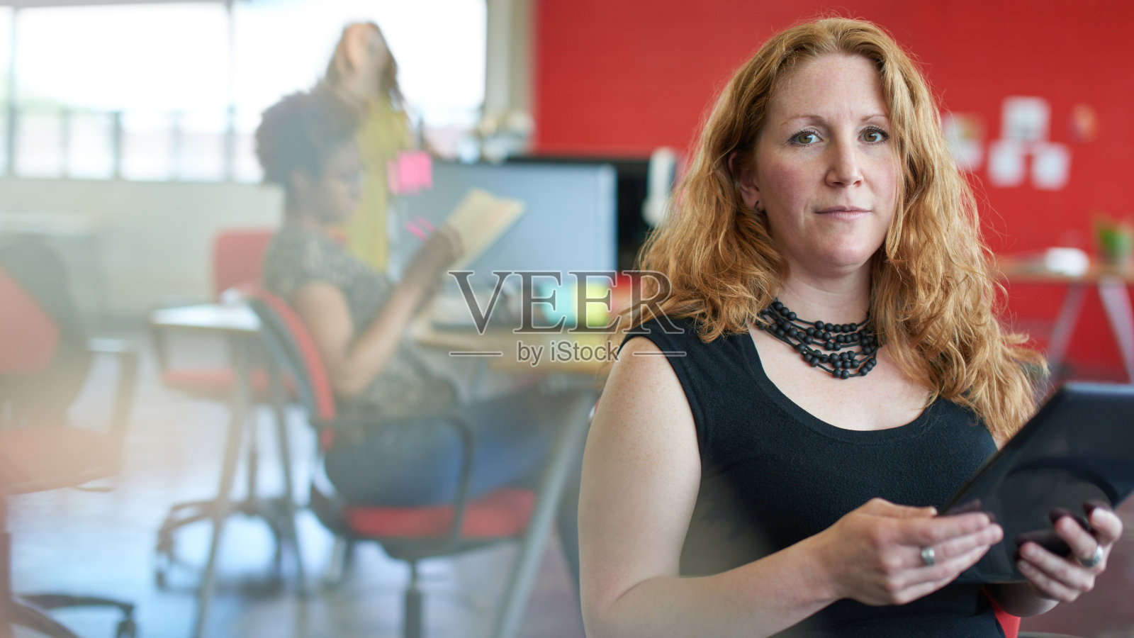 自信的女性设计师在红色的平板电脑上工作照片摄影图片