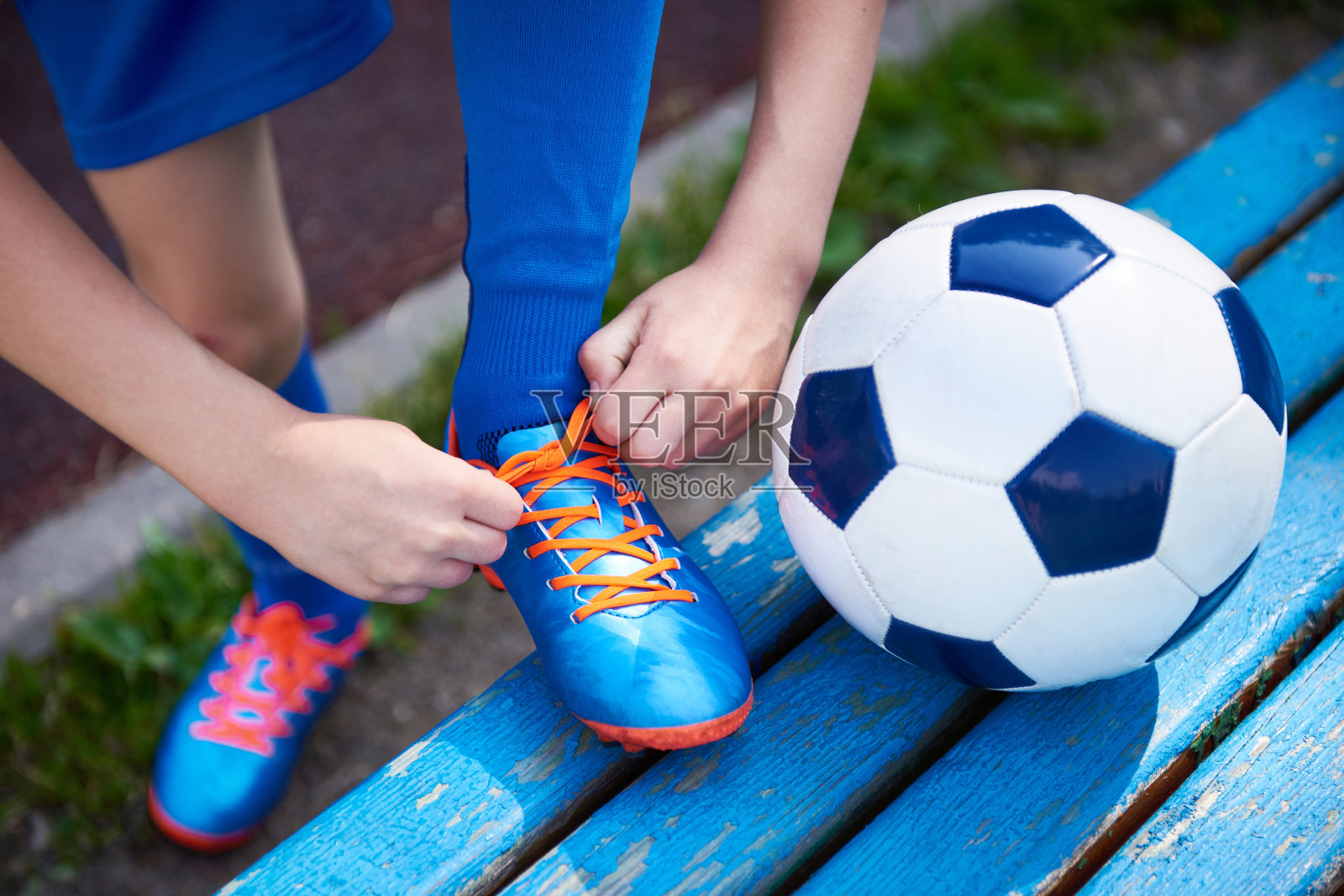 男孩足球系鞋带的靴子在长凳上照片摄影图片