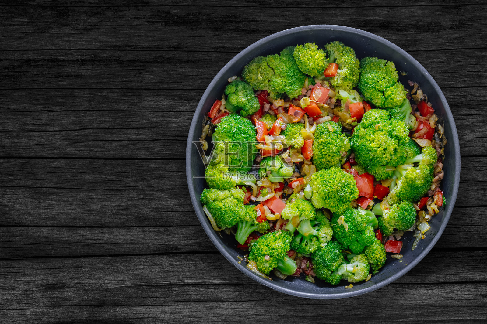 新鲜的夏季沙拉。清炒蔬菜、西兰花、酱油、伊比利亚火腿丁放在质朴的木桌上。健康食品的概念。照片摄影图片