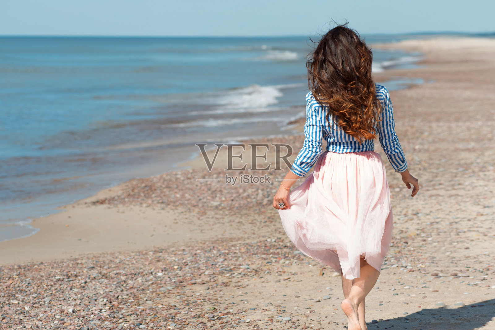 美丽又时尚的黑发姑娘在海滩上散步。后视图照片摄影图片