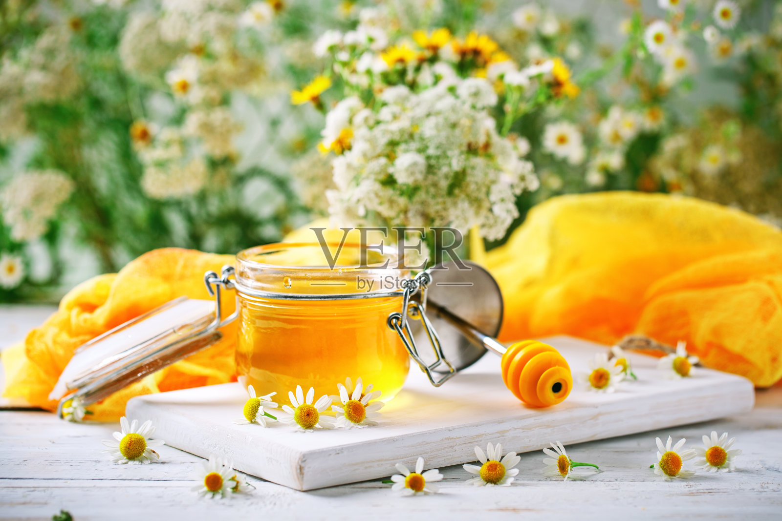白色木桌上放着香甜健康的蜂蜜和洋甘菊花照片摄影图片