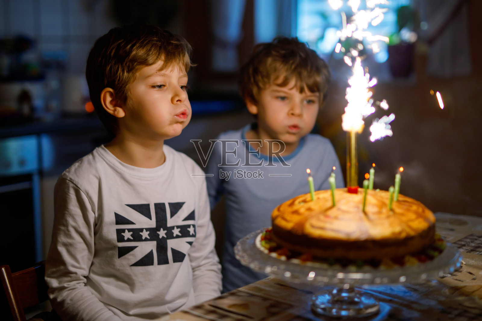 两个漂亮的孩子，学龄前的小男孩在庆祝生日，吹蜡烛照片摄影图片
