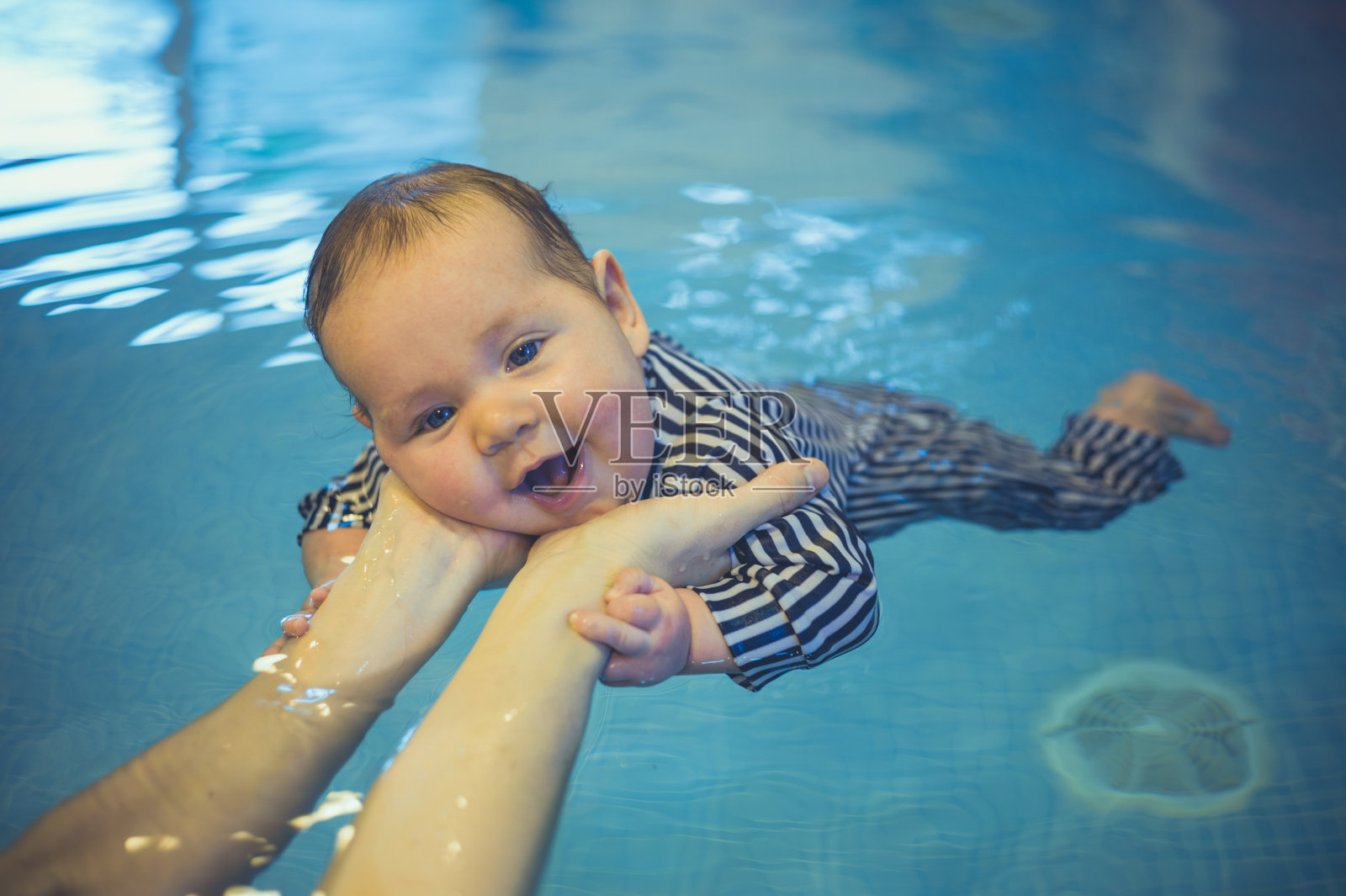 小婴儿在游泳池里游泳照片摄影图片