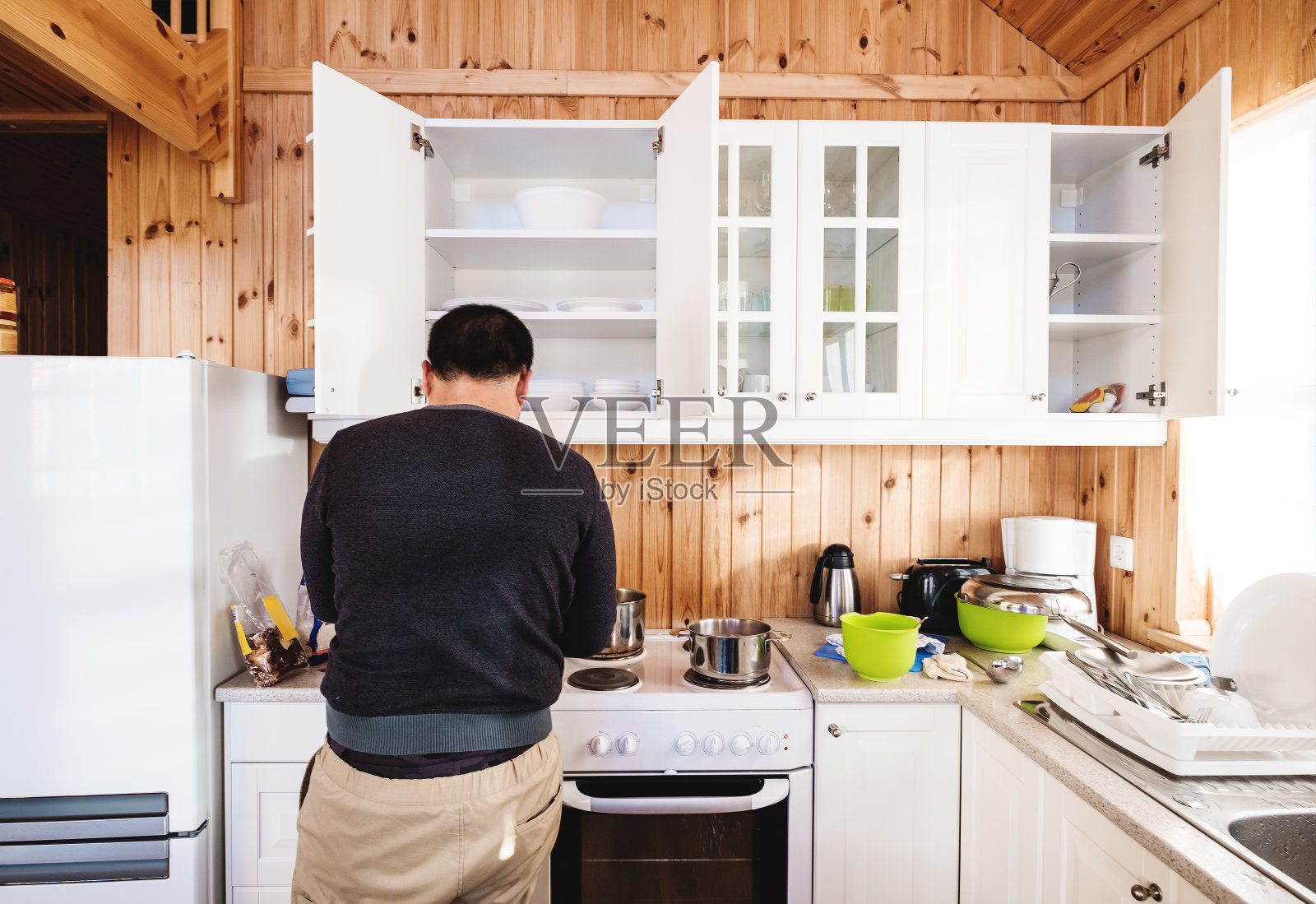 后视图一个男人在厨房准备早餐，在早上照片摄影图片