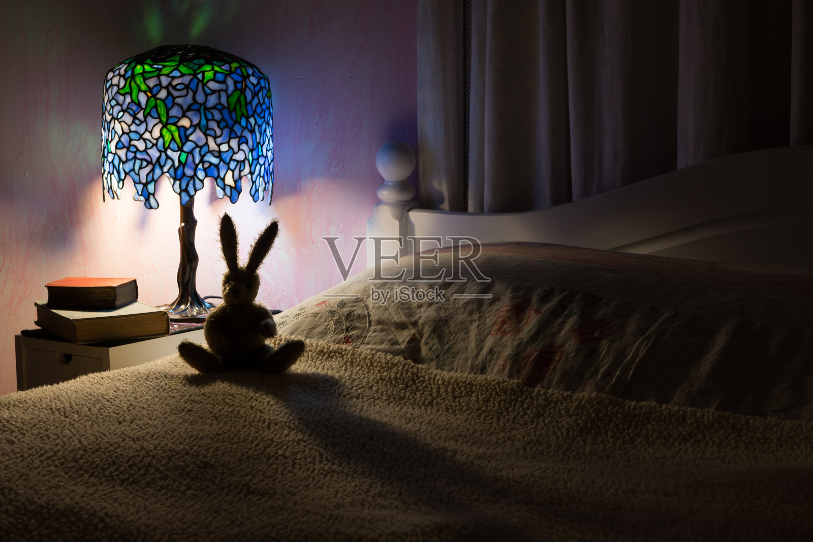 玩具兔子在卧室里被灯照亮了。照片摄影图片