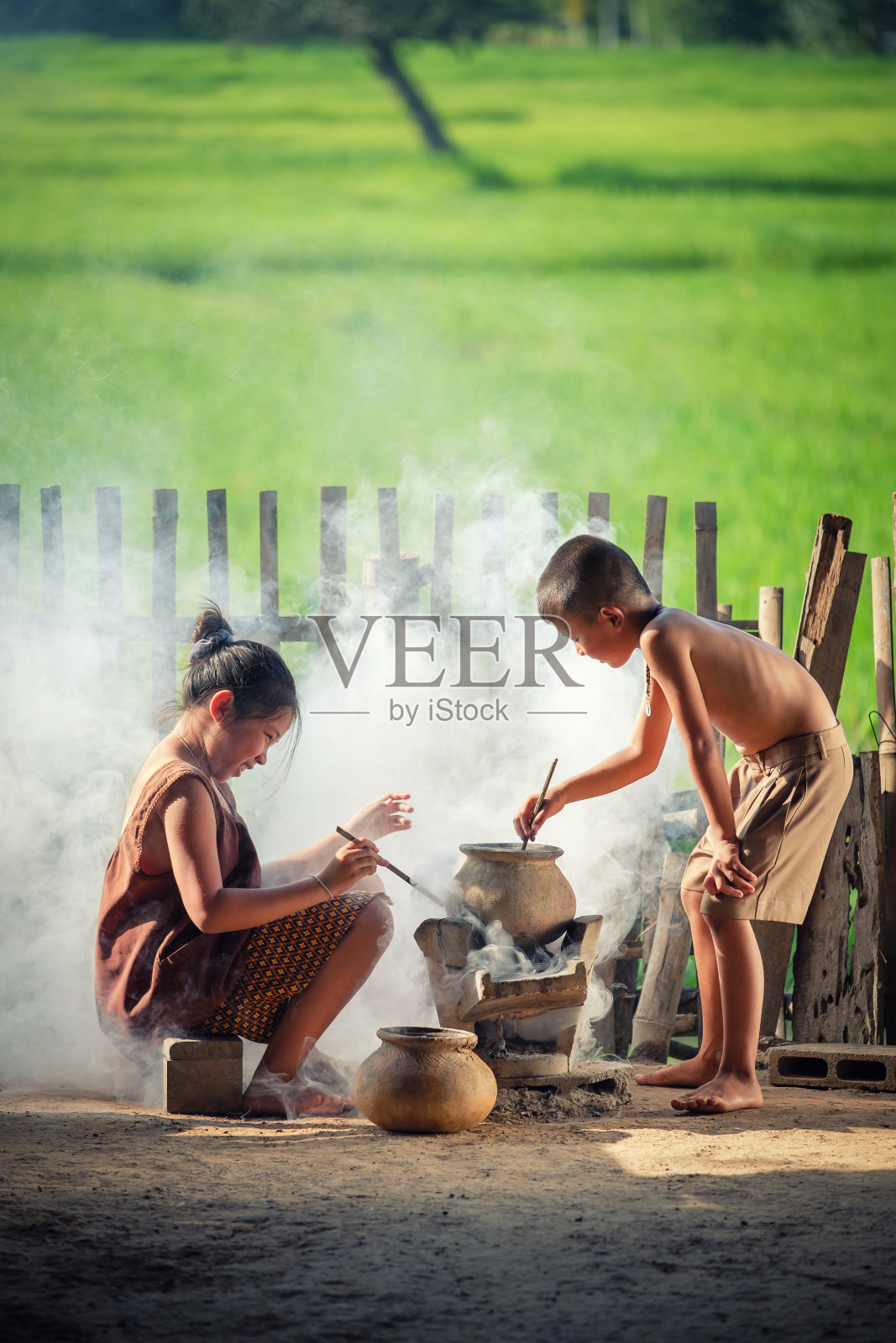 亚洲儿童男孩和女孩在泰国乡村厨房做饭，生活在农村，泰国乡村。照片摄影图片