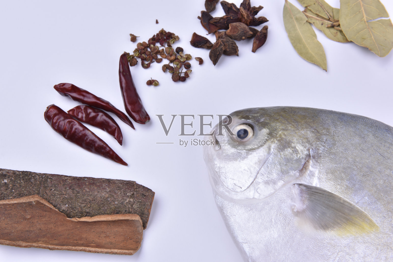 Fresh pompano and a variety of spices on white background.照片摄影图片