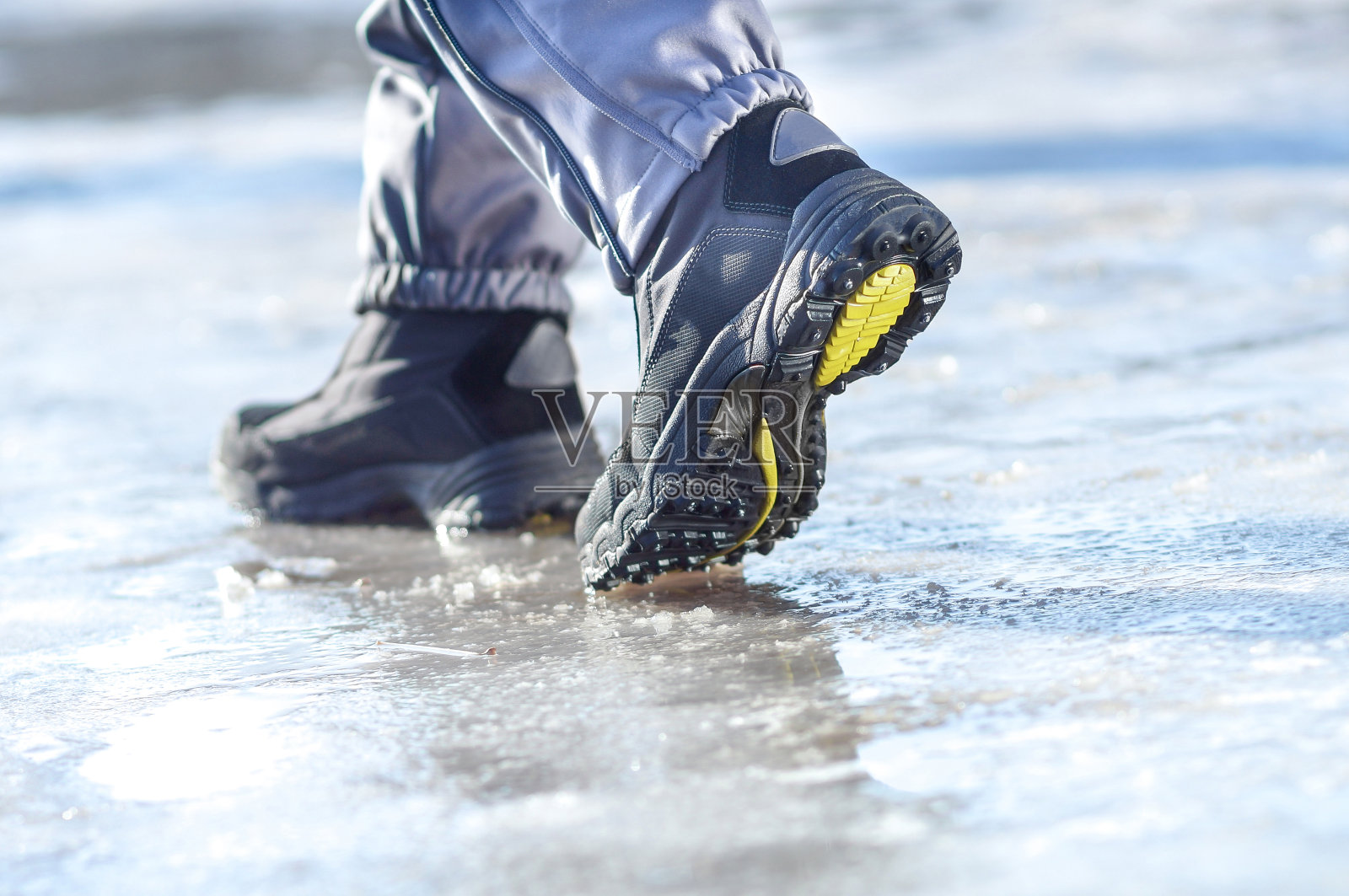 冬天的腿穿着靴子走在冰雪覆盖的路上照片摄影图片