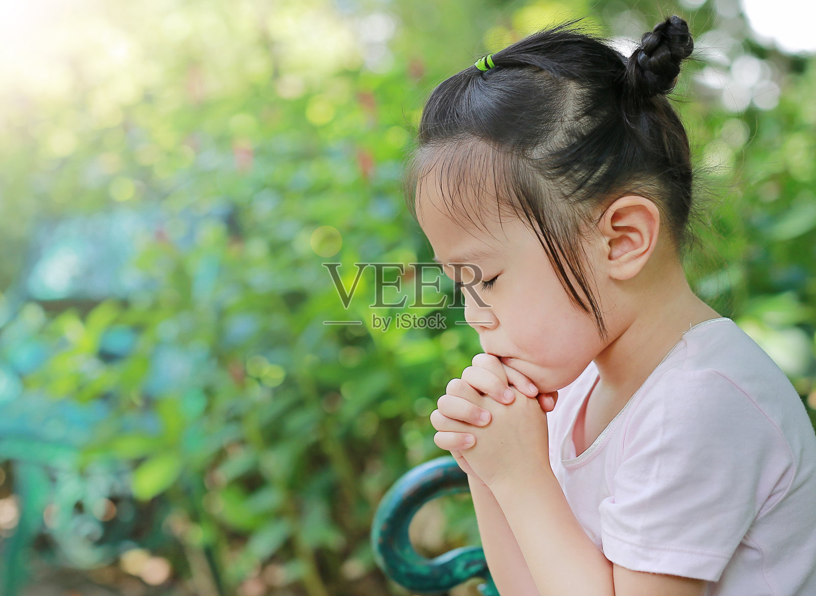 小女孩在花园里祈祷。照片摄影图片