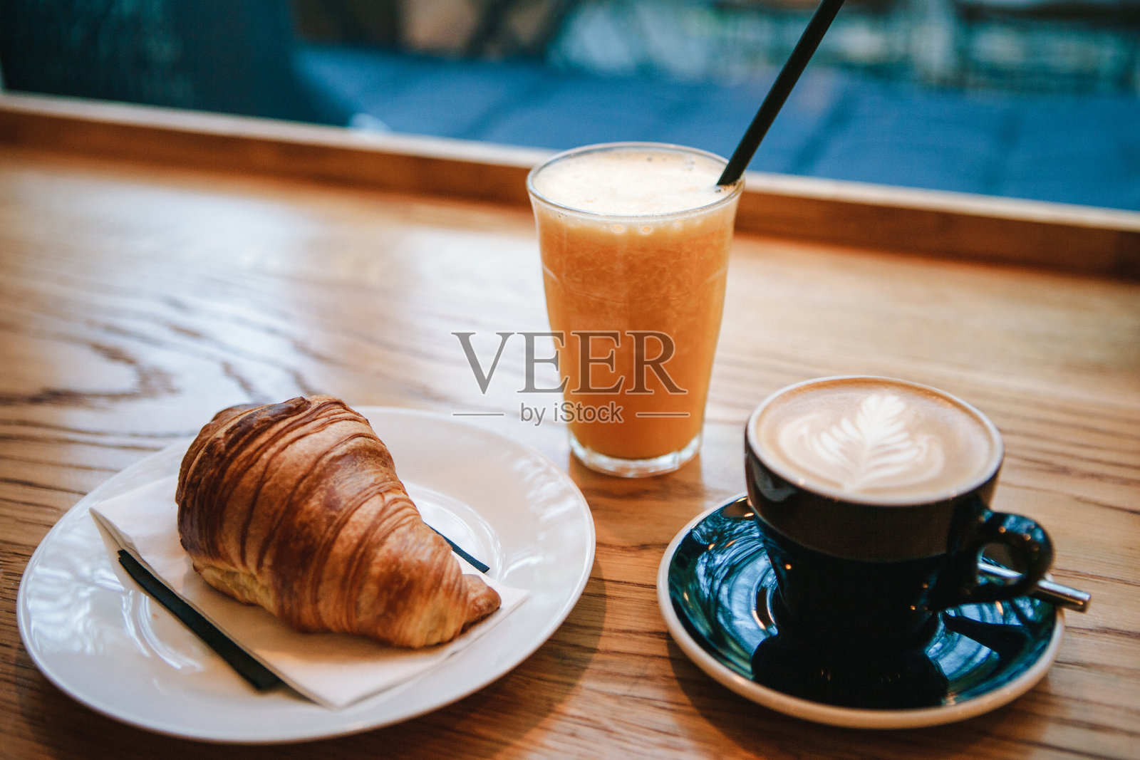 法式传统羊角面包甜点，在咖啡馆里的咖啡卡布奇诺和橙汁旁边作为早餐。照片摄影图片