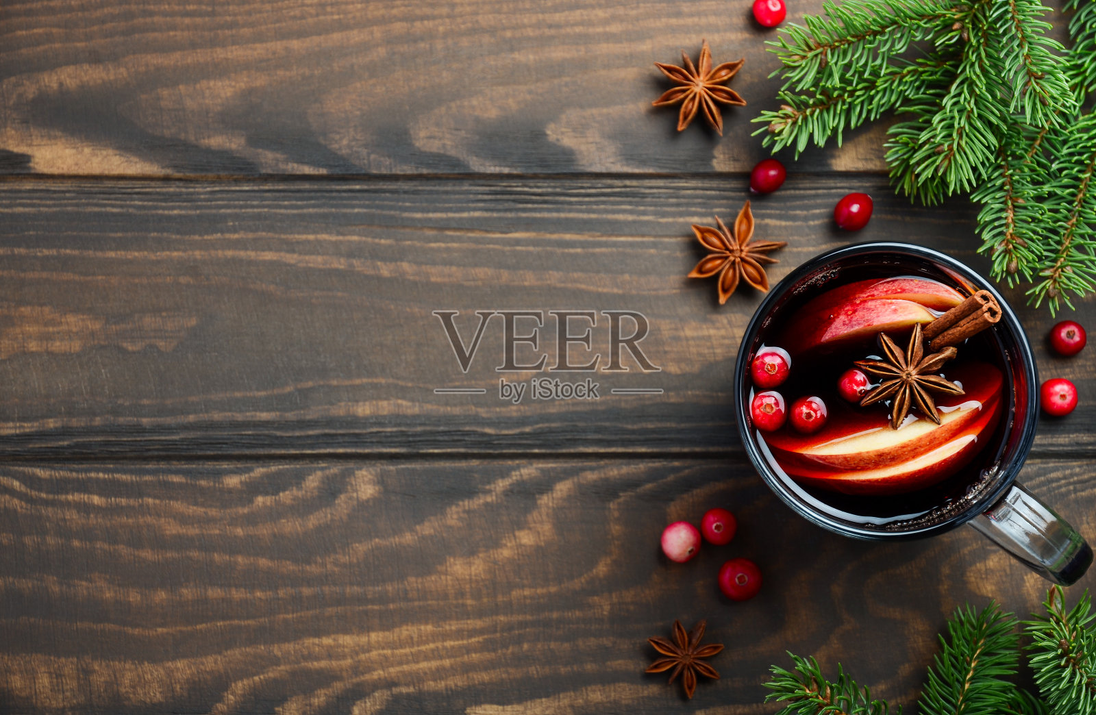 圣诞热葡萄酒与苹果和蔓越莓。用冷杉枝，蔓越莓和香料装饰的假日概念。照片摄影图片