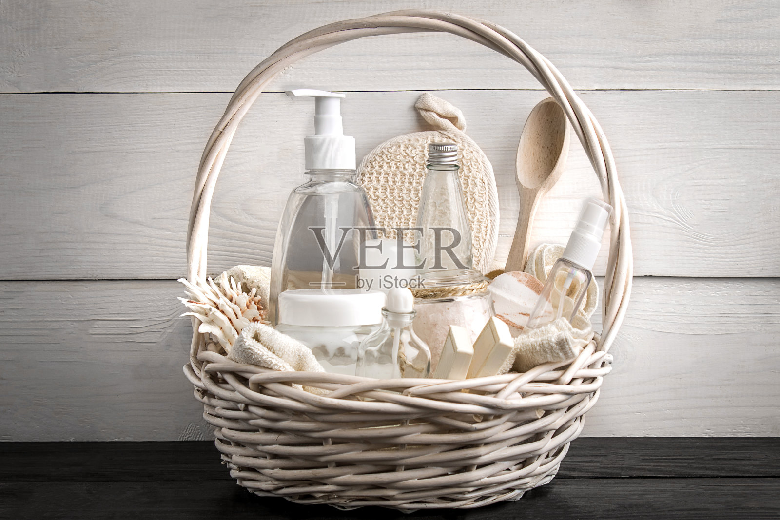 化妆瓶和肥皂组成的篮子，在白色的木制背景照片摄影图片