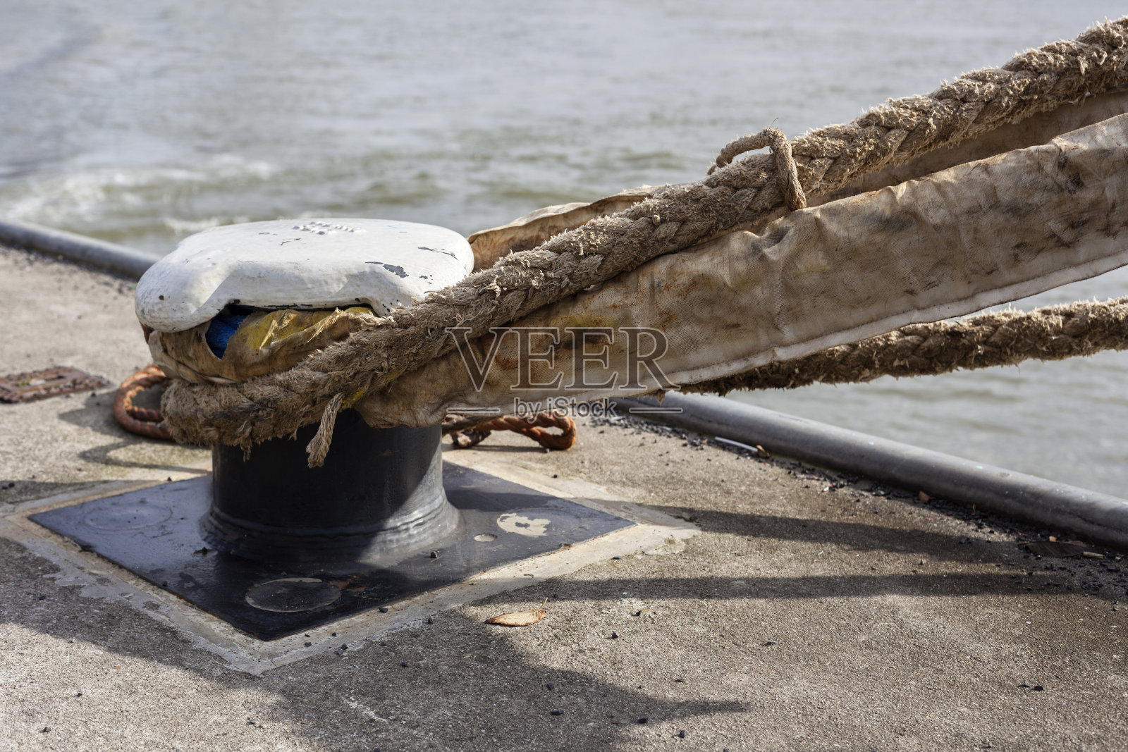 粗大的船绳系在生锈的旧系柱上照片摄影图片