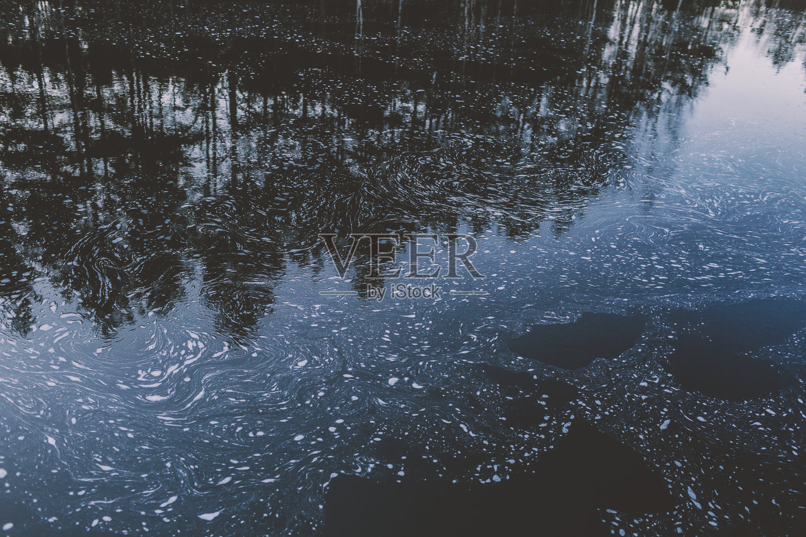 深蓝色的水，白色的泡沫和森林的倒影照片摄影图片