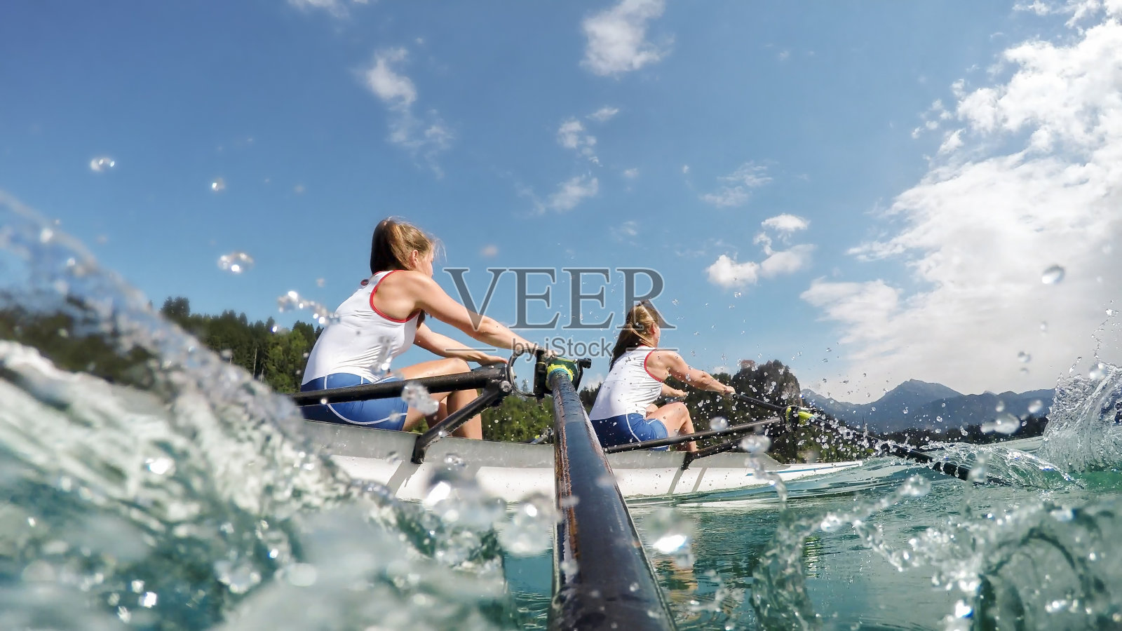 下午晚些时候，两名女运动员划船横渡湖泊照片摄影图片