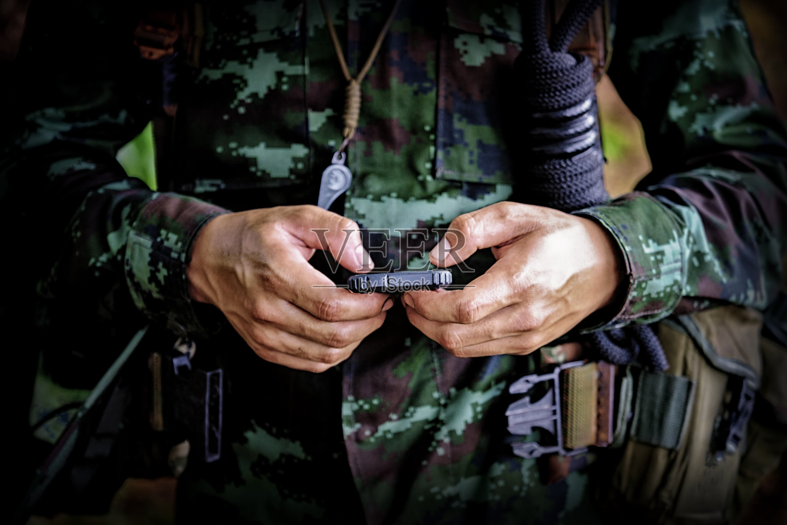 新兵训练营战争中士兵使用手机的中间部分。历史重演一个士兵和一个过时的手机来发短信照片摄影图片