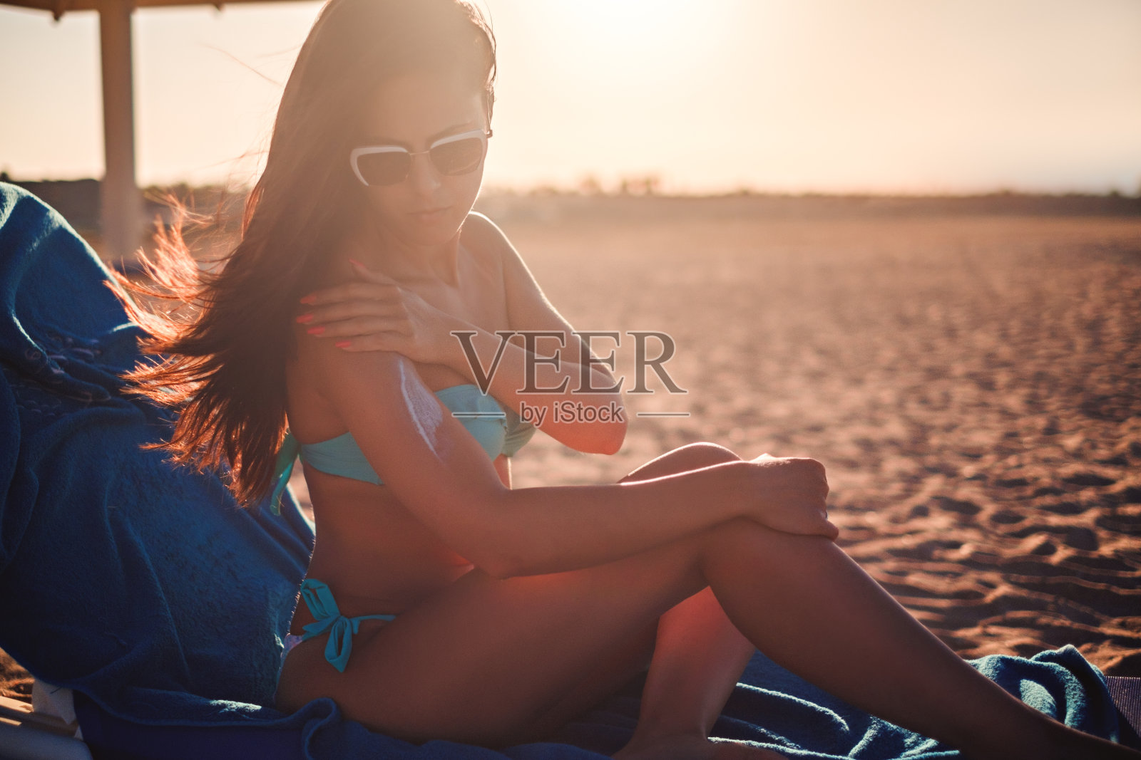 坐在海滩上涂抹防晒霜的女孩照片摄影图片