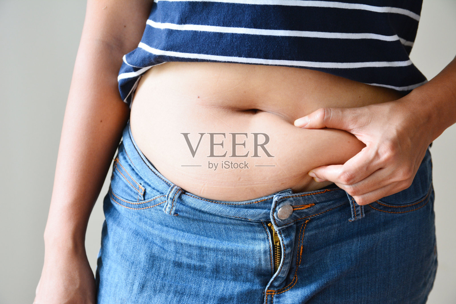 女人身上的脂肪用手捧着肚子上过多的脂肪照片摄影图片