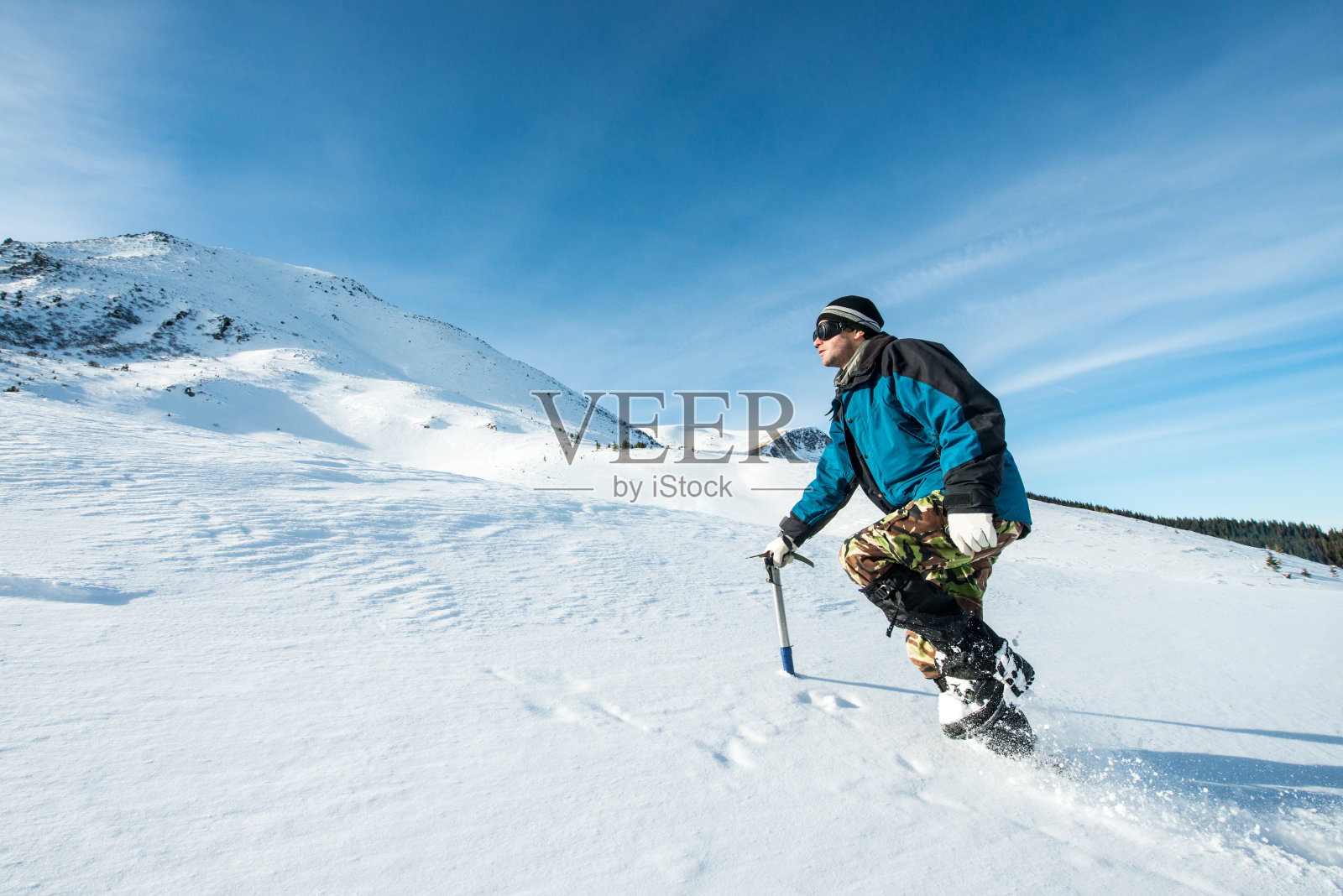 登山者拿着冰斧在雪山中行走照片摄影图片