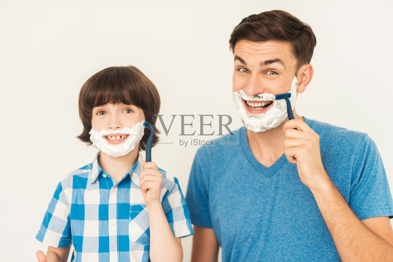 父亲在浴室里教儿子刮胡子。照片摄影图片