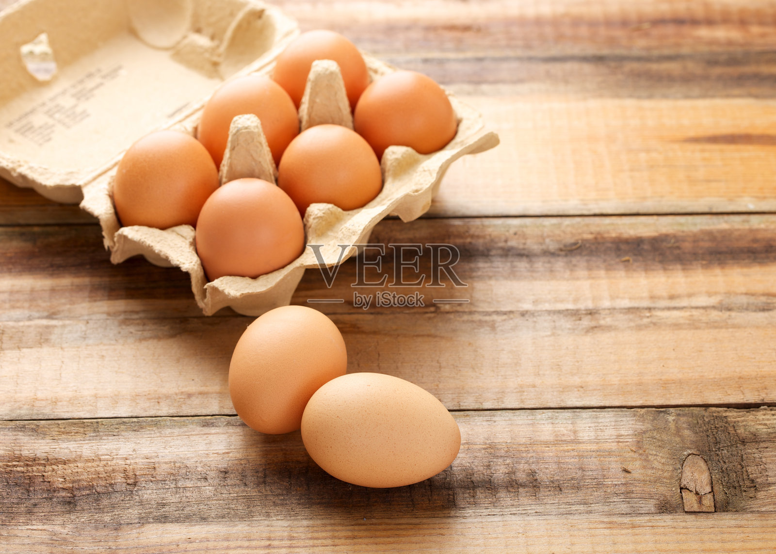 新鲜的鸡蛋放在鸡蛋盒里，木制的背景照片摄影图片