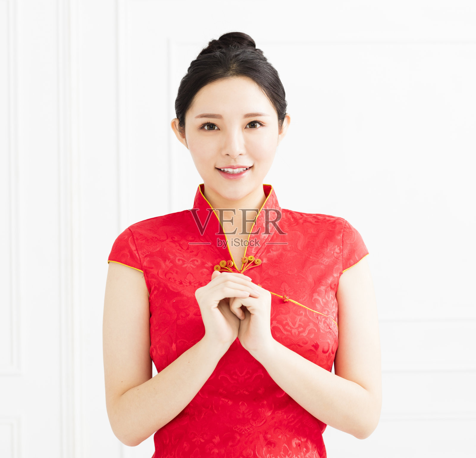 身着中国旗袍、摆着祝贺手势的年轻女子照片摄影图片