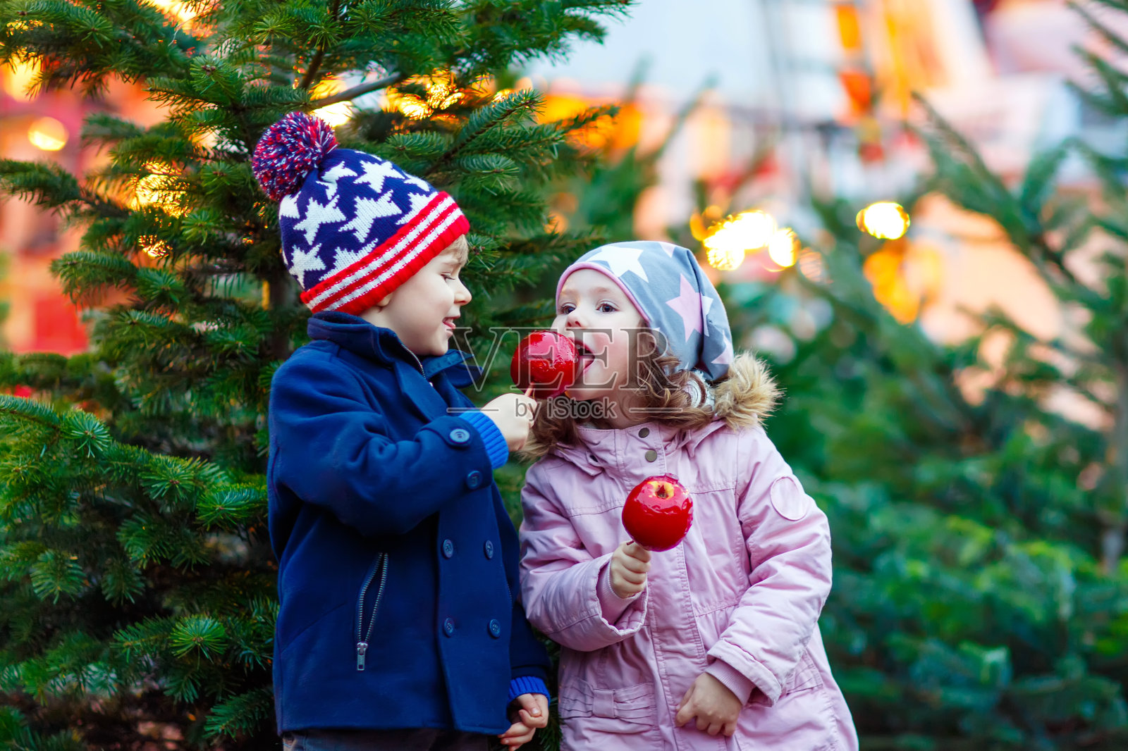 两个小孩在圣诞市场上吃水晶苹果照片摄影图片
