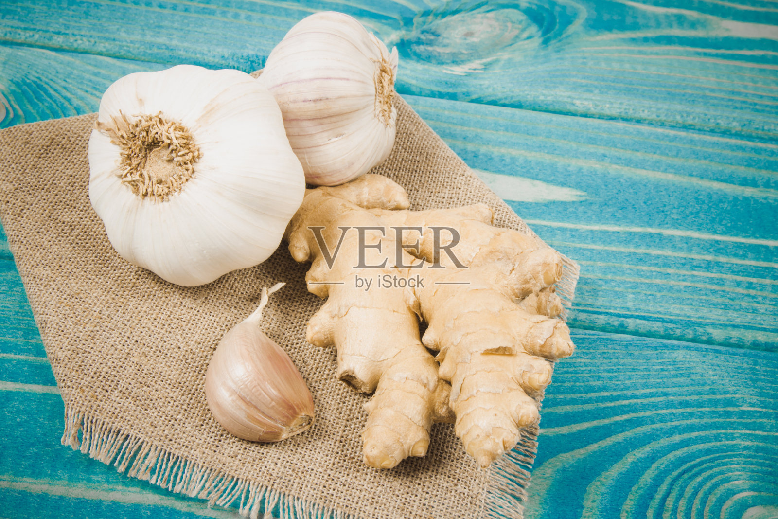 蓝色的木桌上放着大蒜和姜。自然医学的概念。照片摄影图片