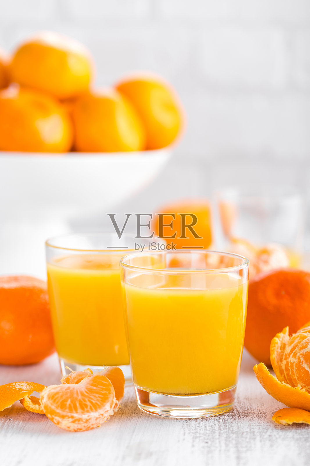 橘子，去皮的橘子和橘子汁在玻璃杯里。柑桔汁。照片摄影图片