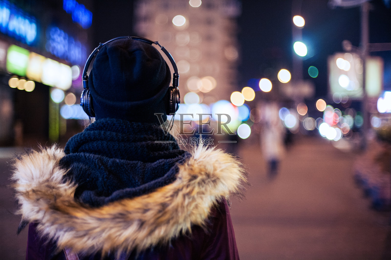 女孩走在夜晚的城市街道听着音乐照片摄影图片