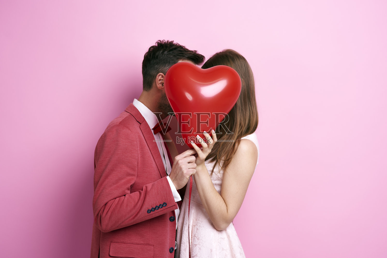 深情的夫妇用气球覆盖脸和亲吻照片摄影图片