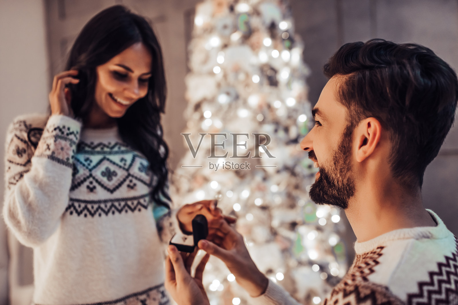 美丽的情侣在家里美丽的圣诞树旁一起等待新年。照片摄影图片