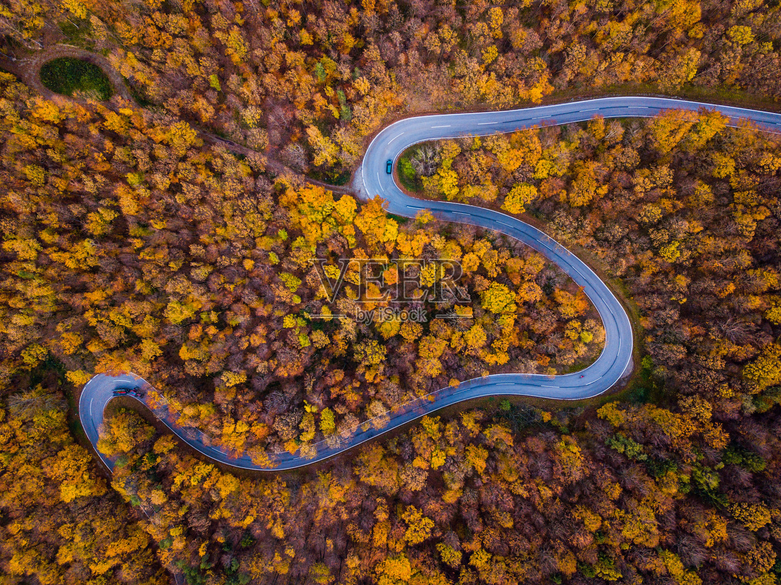 无人机:空中公路之旅——五彩缤纷的秋天森林里弯曲的乡村公路照片摄影图片