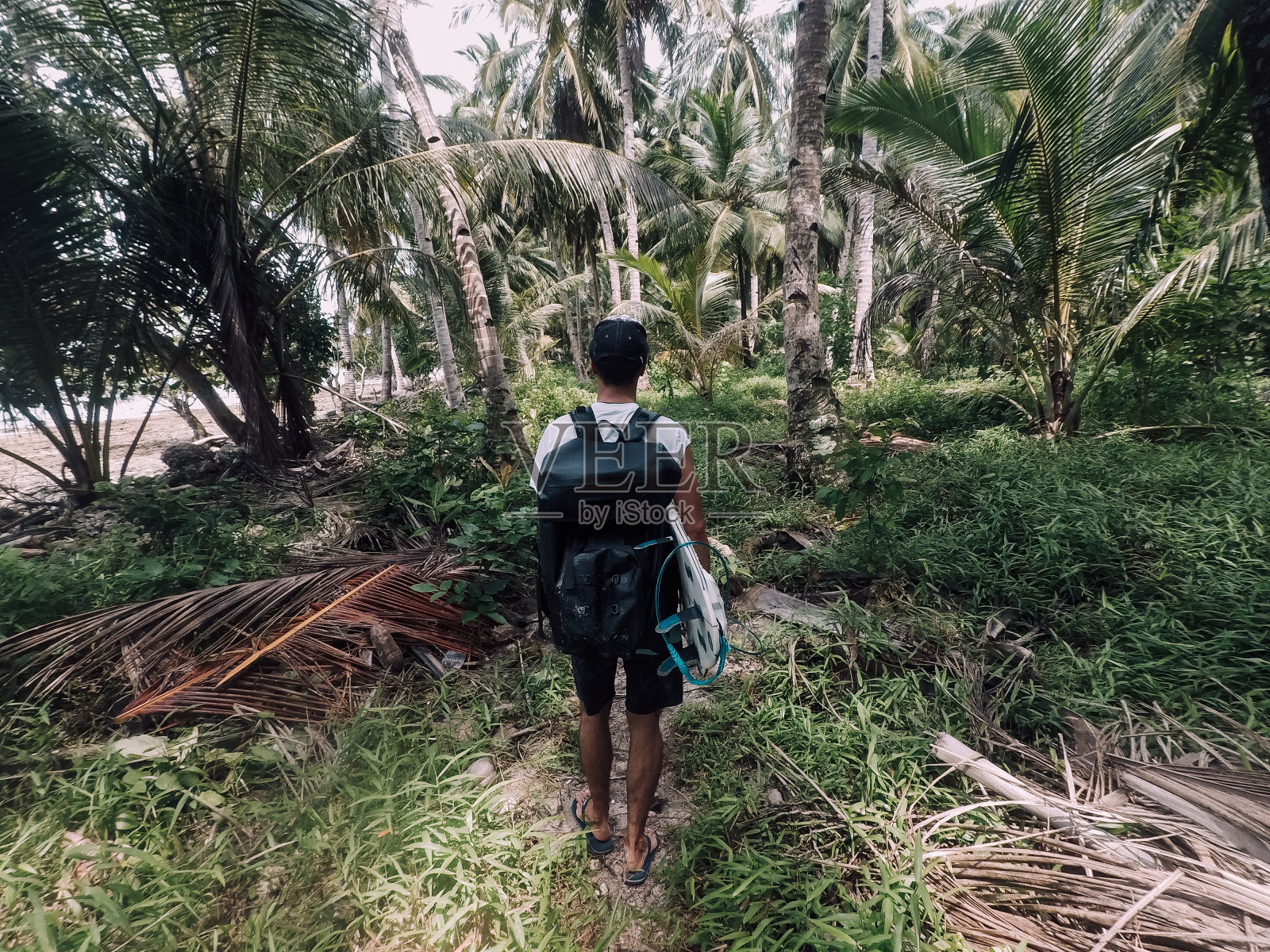 背着背包在棕榈树下行走的冲浪者照片摄影图片