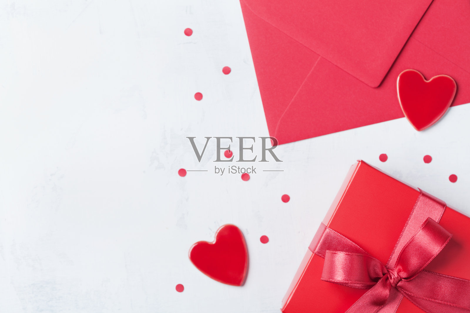 情人节礼物，信封和红心放在白色的桌子上。照片摄影图片