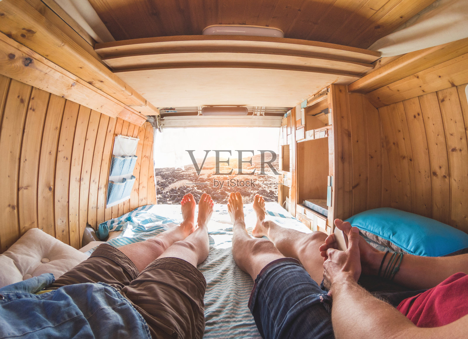 在日落的小货车里快乐的夫妇的观点-年轻人有乐趣的暑假-旅游，爱和自然的概念-关注脚-温暖的对比过滤器照片摄影图片