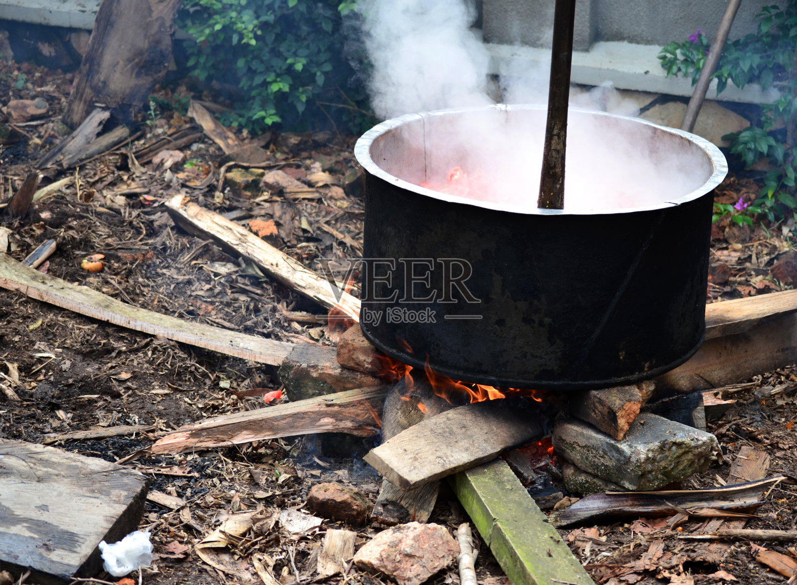 在火坑上一个又脏又旧的炖锅里做饭。照片摄影图片