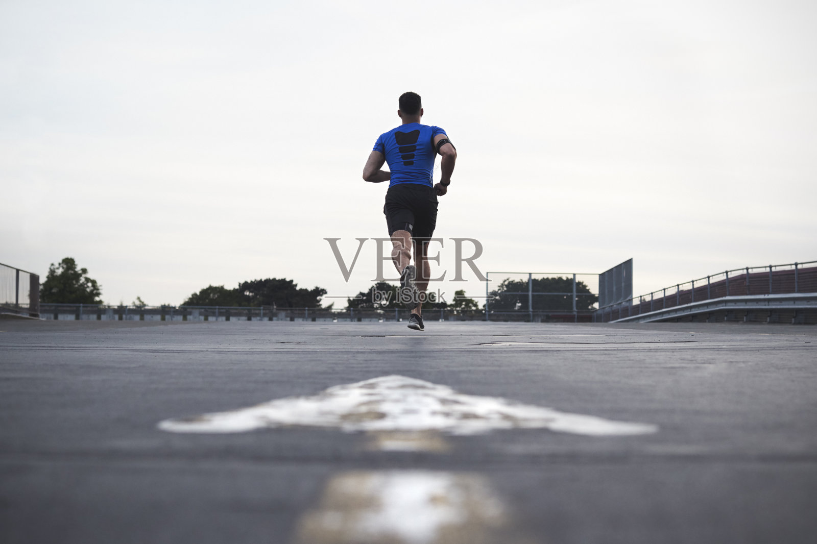 男运动员在远离镜头的马路上跑，全程照片摄影图片