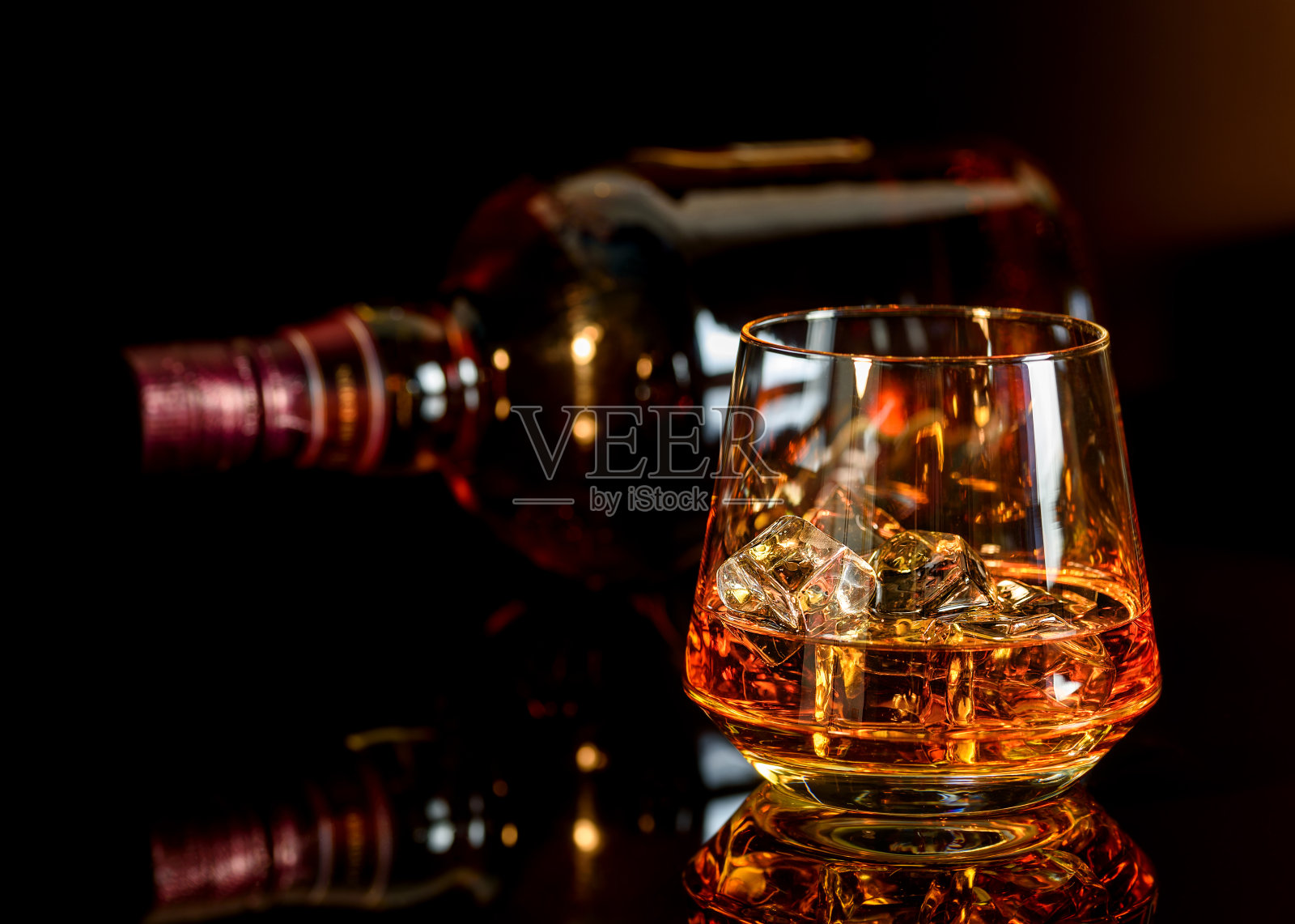 威士忌加冰玻璃杯和一瓶威士忌在黑色背景照片摄影图片
