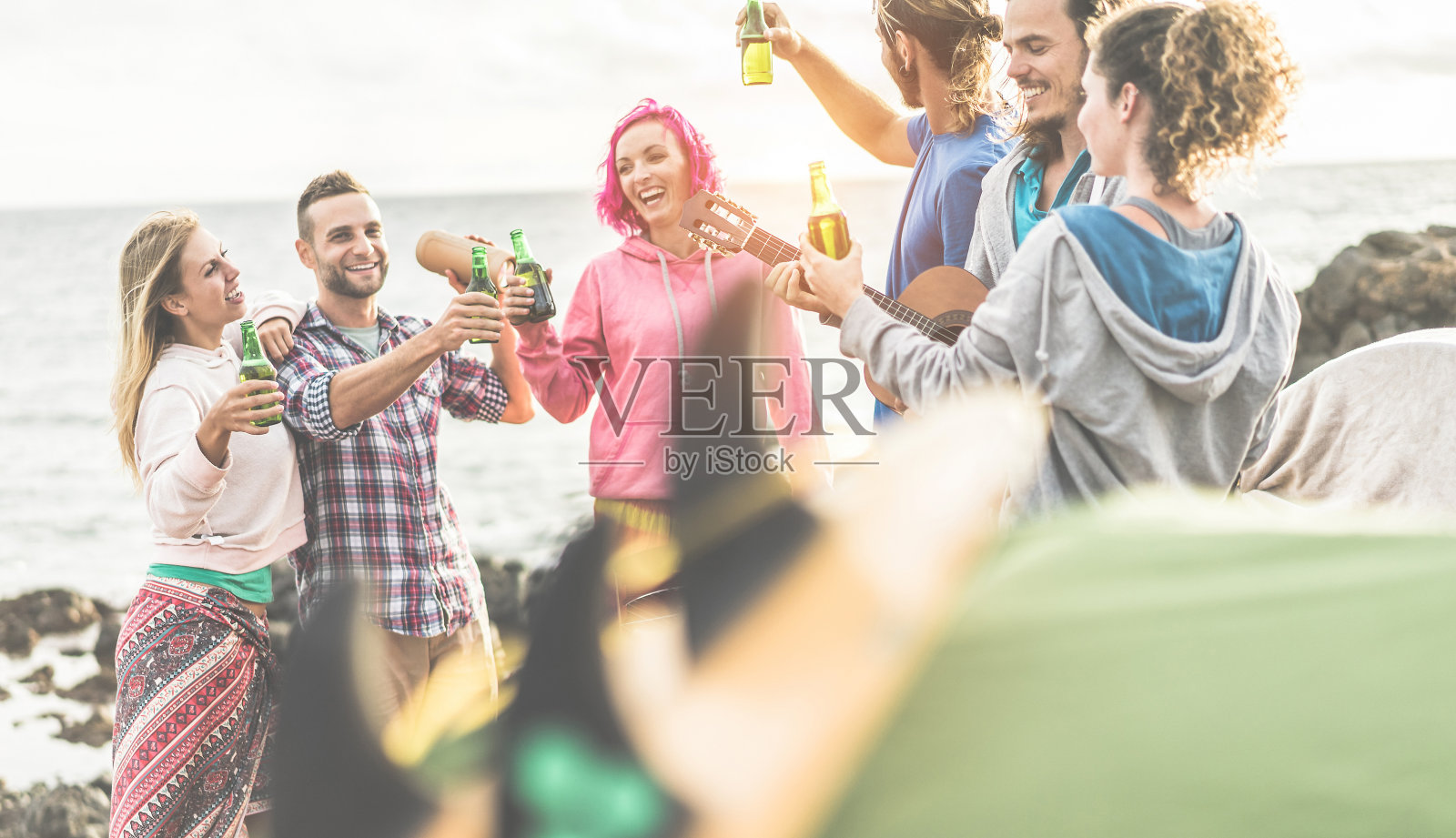 一群快乐的朋友欢呼与啤酒在露营-时髦的人有乐趣玩音乐和一起大笑-聚焦左女人-旅行，度假，派对和友谊的概念照片摄影图片