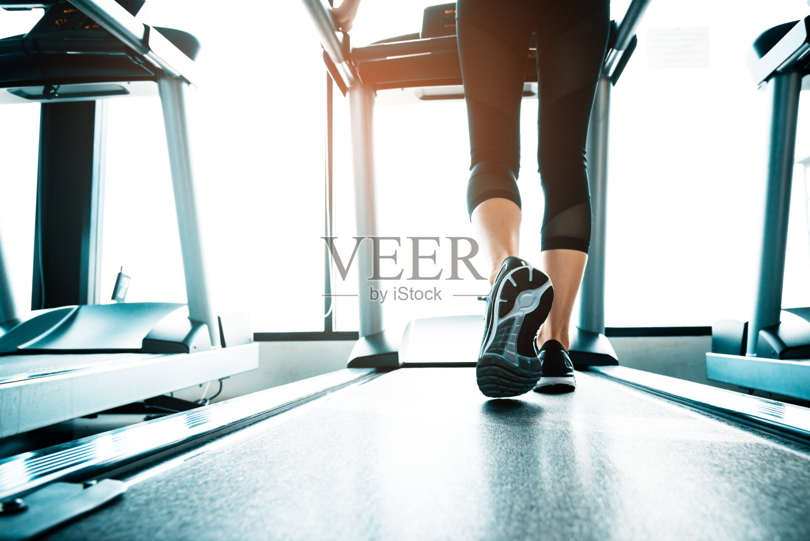 近距离观察在跑步机上锻炼的人。特写的女人的腿走在跑步机上在体育俱乐部。健身和身体建立概念。锻炼和力量训练的概念。体育俱乐部的主题。照片摄影图片