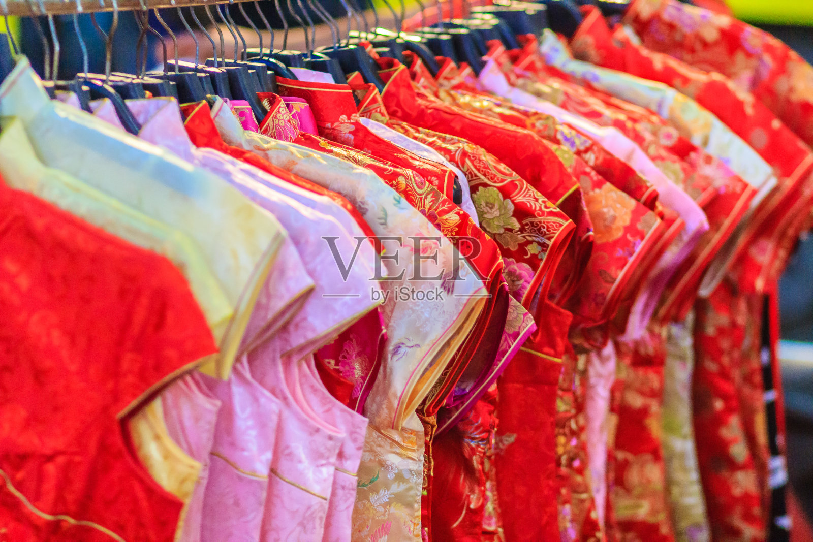 春节期间，在泰国曼谷，漂亮的旗袍(旗袍或中国服装)挂在晾衣绳上，夜市出售给顾客。照片摄影图片