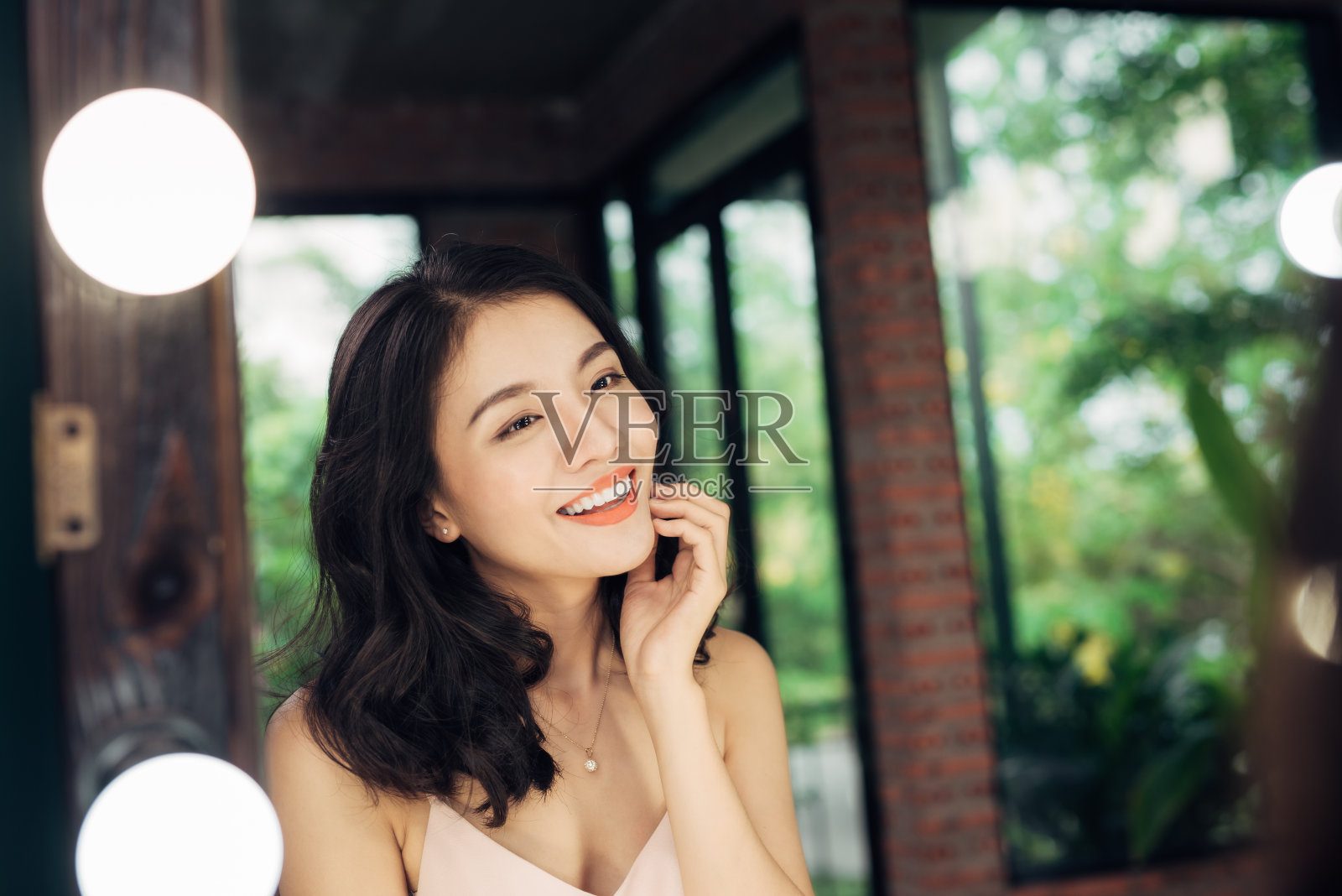 一个很快乐的亚洲女人在家里的大镜子里看着自己。照片摄影图片