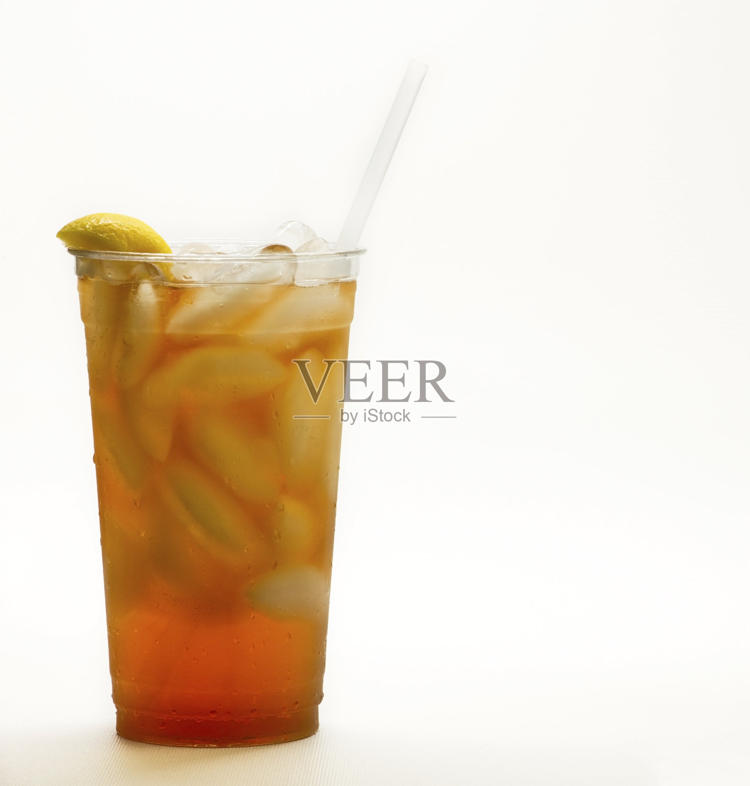 新鲜的冰茶在一个透明的杯子，一个柠檬和一根吸管在白色的背景。照片摄影图片