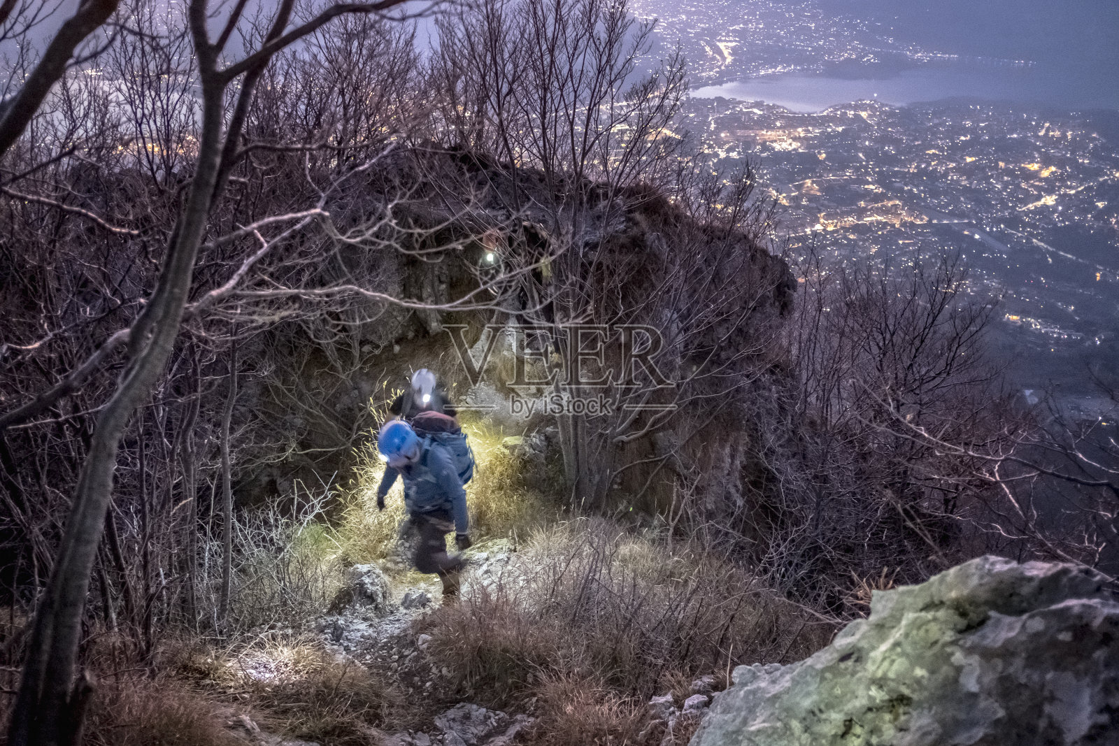 夜间在山上徒步穿越城市的登山者照片摄影图片