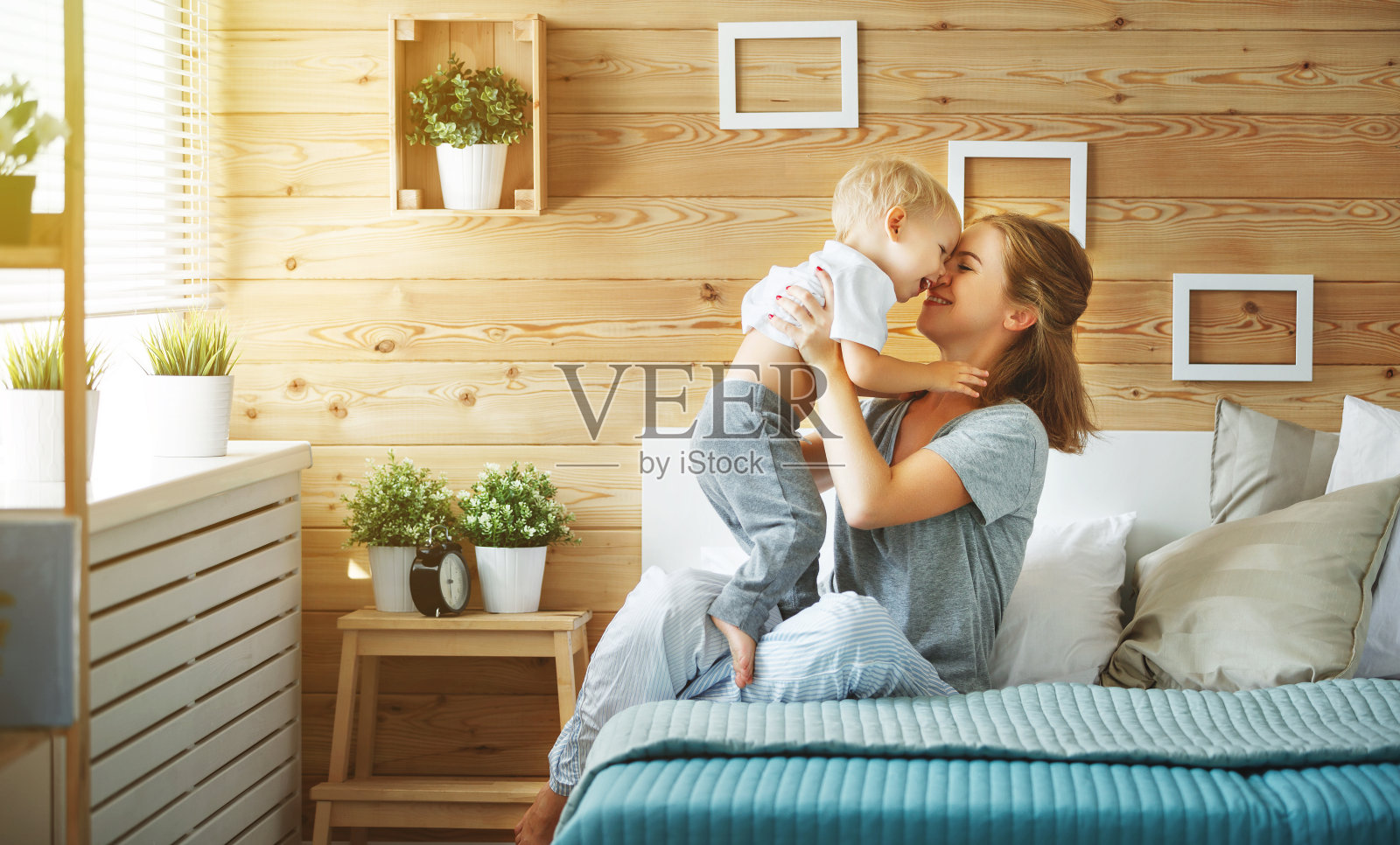 幸福的家庭母亲和婴儿儿子学步在床上笑照片摄影图片