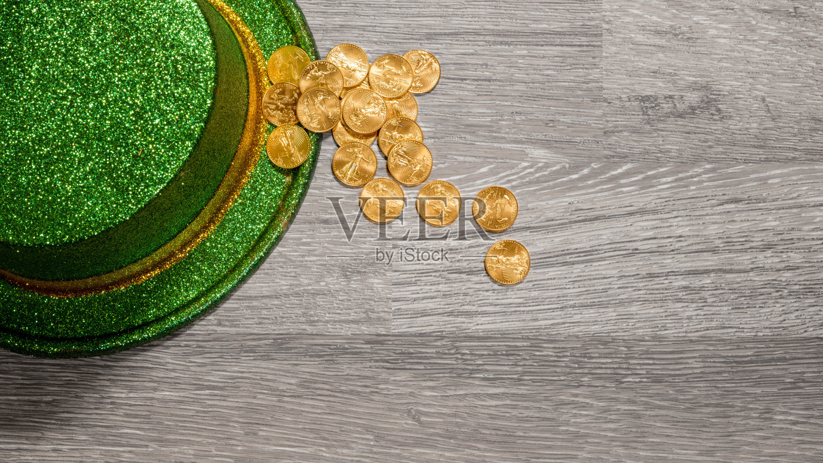 在圣帕特里克节绿色帽子的边缘内堆着纯金硬币照片摄影图片