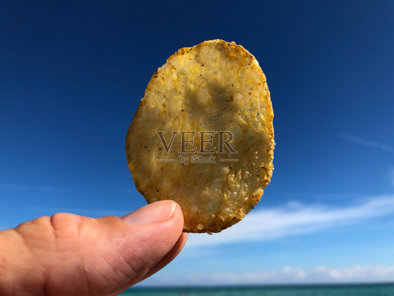在海滩手握薯片照片摄影图片